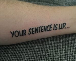Tattoo on a forearm reading “YOUR SENTENCE IS UP…” — a personal reminder of narrative transformation and the freedom to rewrite one's story.